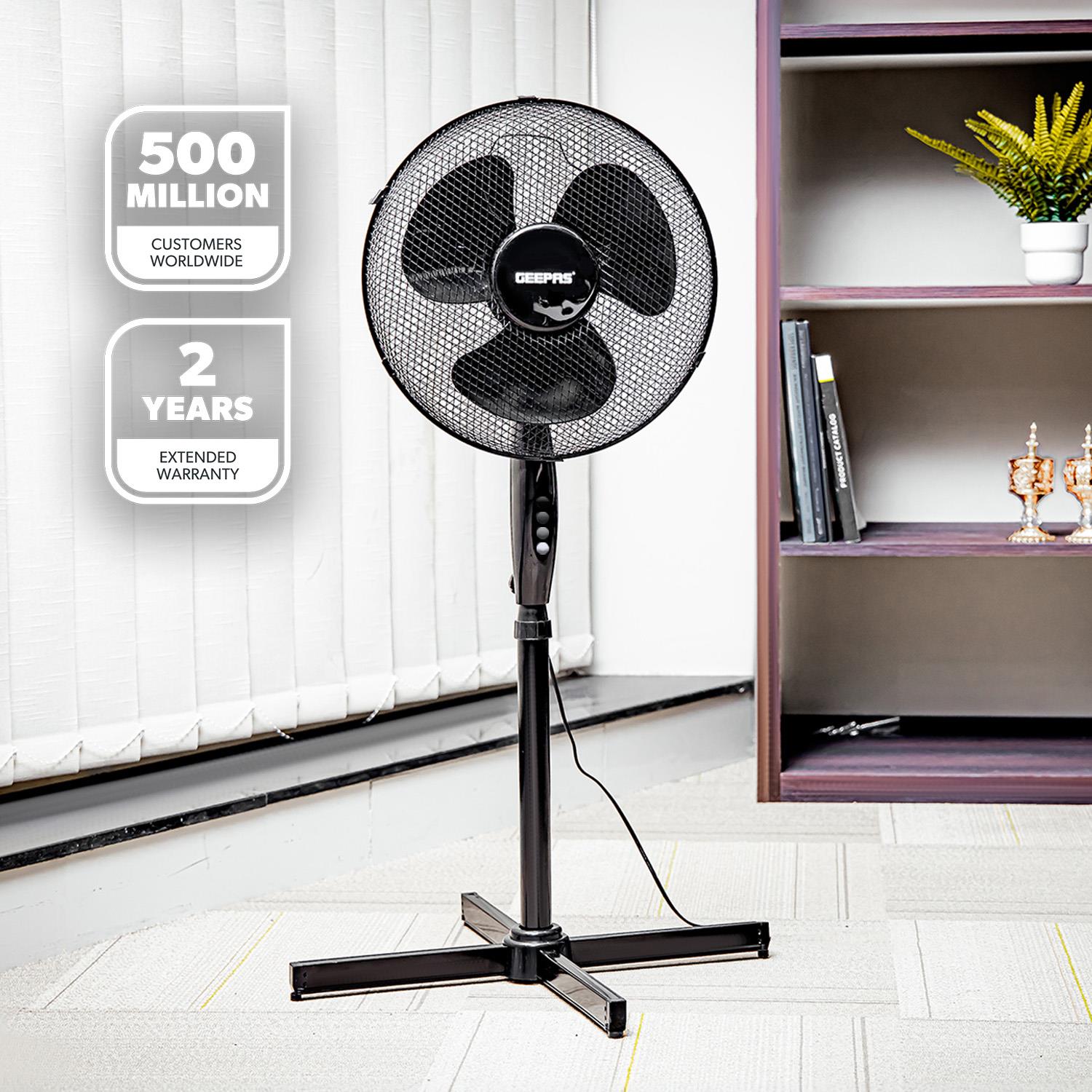The 16 inch black pedestal fan in placed in an office environment for a lifestyle type shot.