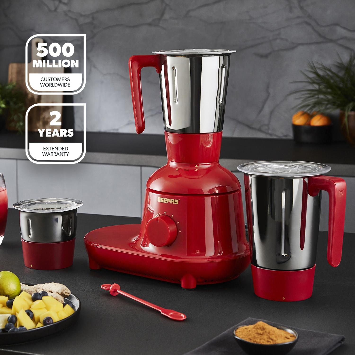 The Geepas red 3-in-1 mixer grinder on a black kitchen countertop with three different grinding jars.
