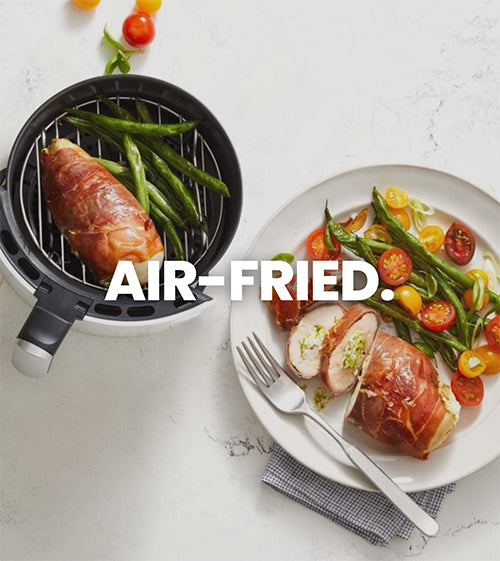 The image shows a dinner plate with with air fried chicken and an air fryer basket next to it with food ready to be air fried