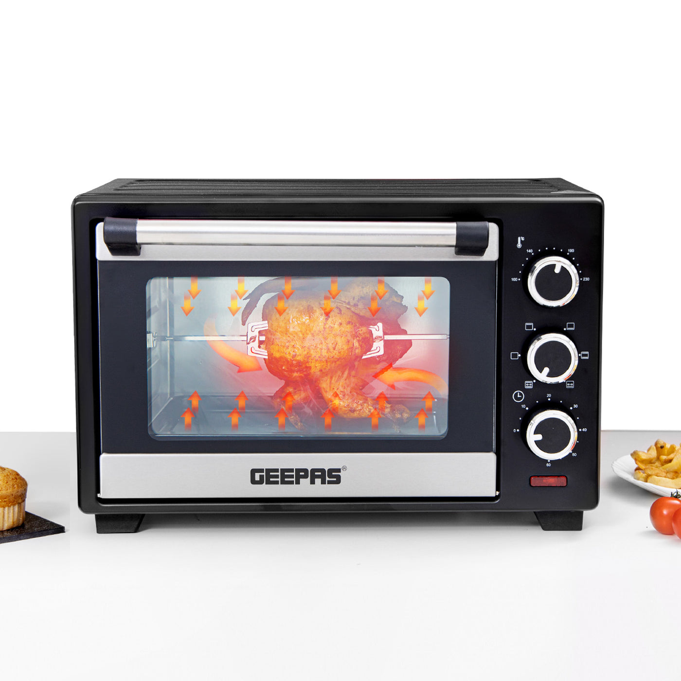 The image shows off the electric mini oven on top of kitchen countertop, showing off the rotisserie functionality with a whole chicken cooking inside.