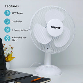 The white cooling fan is resting on a white desk besides a laptop and a notebook displaying the four main features of the fan.